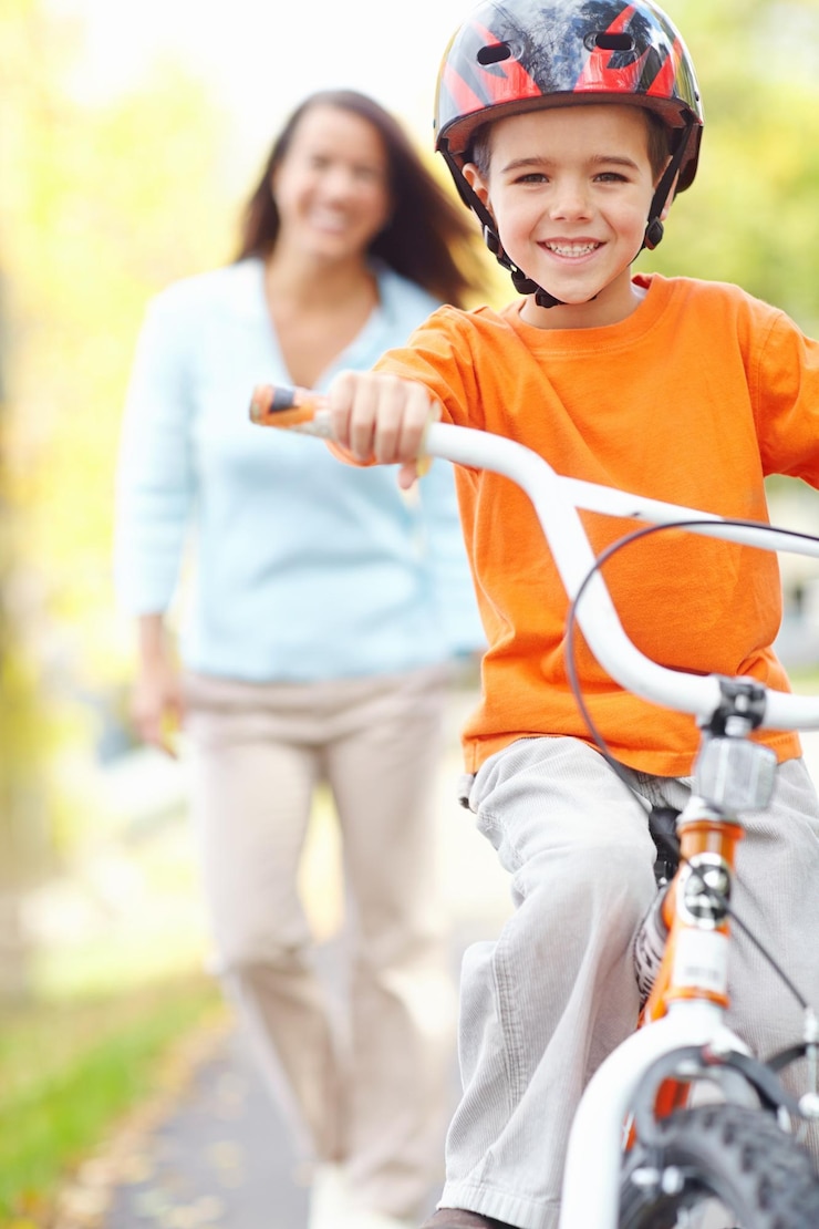 Foto aprendizagem de bicicleta e retrato de filho com a mãe ao ar livre na rua do bairro para o desenvolvimento da criança família feliz ou sorriso com mãe solteira mulher ensinando menino como equilibrar ou andar de bicicleta