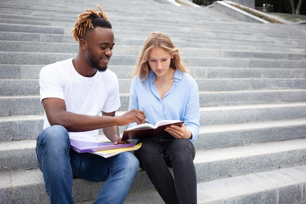 Aprendizagem educacional e conceito de pessoas jovens dois amigos multirraciais sentados em escadas no parque
