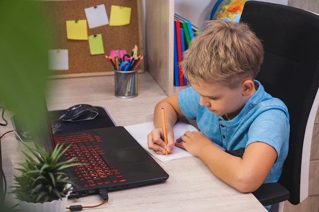 Aprendizaje a distancia educación en línea Colegial aprendiendo en línea en casa en la mesa usando una computadora portátil