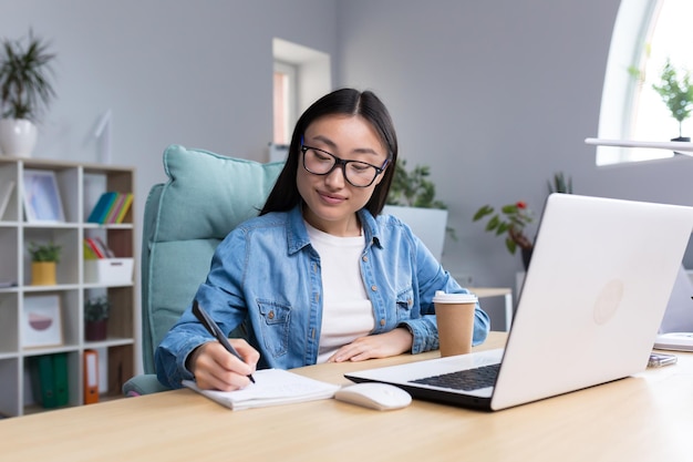 Aprendizaje a distancia joven hermosa estudiante asiática tomando un examen en línea sentado en gafas y