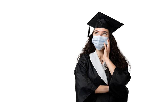 Aprendizaje a distancia en línea con máscara médica en el período coronavirus covid-19. Estudiar en casa. Graduación de la universidad. Licenciado en túnica negra sonriendo. Terminar la universidad y completar la maestría