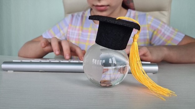 Aprendizaje a distancia y una niña pequeña sentada en casa en la mesa y escribiendo en el teclado de la computadora portátil