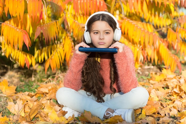 Aprendizaje electrónico hoy Niña pequeña aprendiendo en línea bajo un árbol con hojas amarillas Aprendizaje electrónico de niños pequeños en un día soleado de otoño Aprendizaje electrónico de educación global para el futuro entorno de aprendizaje electrónico