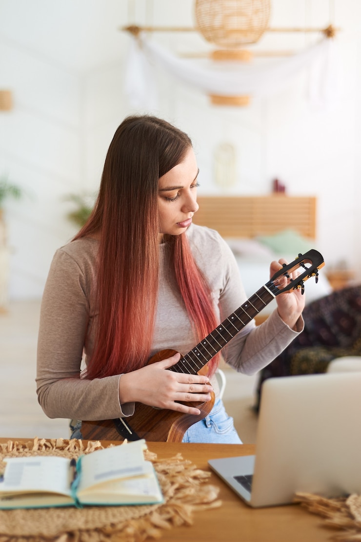 Foto aprendizaje en línea a tocar un instrumento musical. mujer joven afinando el ukelele para lecciones de música.