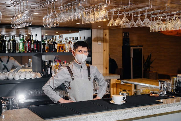 Foto apresentação de um barista em uma máscara de delicioso café orgânico em um café moderno durante a pandemia.