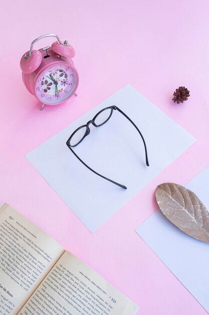 Apresentação do produto do conceito minimalista ideia óculos livro relógio folhas secas em fundo de papel rosa