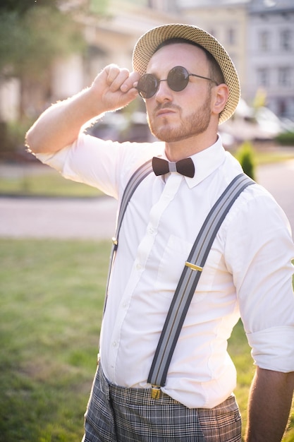 Apresentador bonito e showman em um elegante terno e chapéu com microfone posa com as melhores emoções e truques acrobáticos