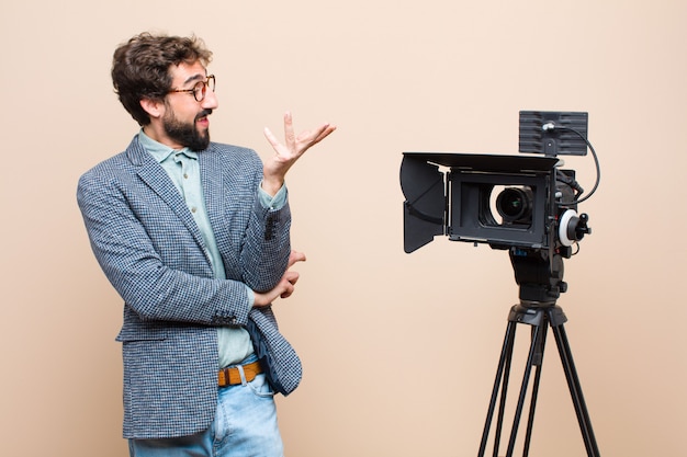 Apresentador de televisão sorrindo com orgulho e confiança, sentindo-se feliz e satisfeito e mostrando um conceito no espaço da cópia