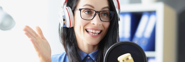 Apresentadora de rádio com fones de ouvido falando no microfone em transmissão de rádio de estúdio