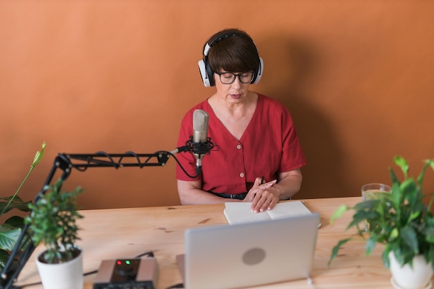 Apresentadora de rádio de mulher de meia idade fazendo gravação de podcast para transmissão de programa online e conceito de dj