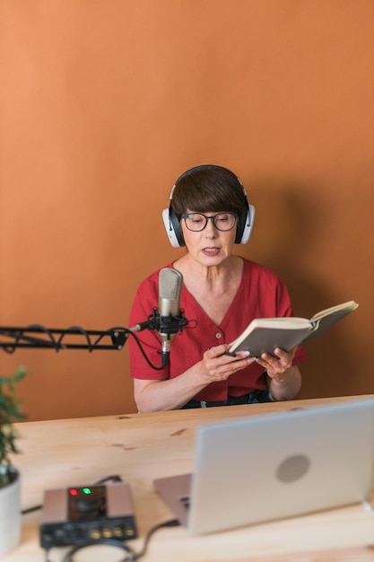 Apresentadora de rádio feminina de meia-idade falando no microfone e lendo notícias de rádio on-line