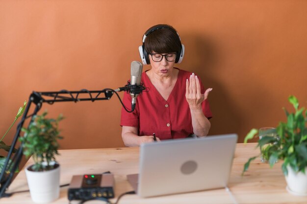 Apresentadora de rádio feminina de meia idade falando no microfone e lendo o conceito on-line de transmissão de notícias de rádio