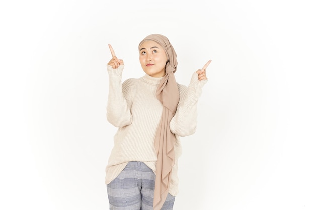 Apresentando e apontando para cima uma bela mulher asiática usando um hijab isolado no fundo branco