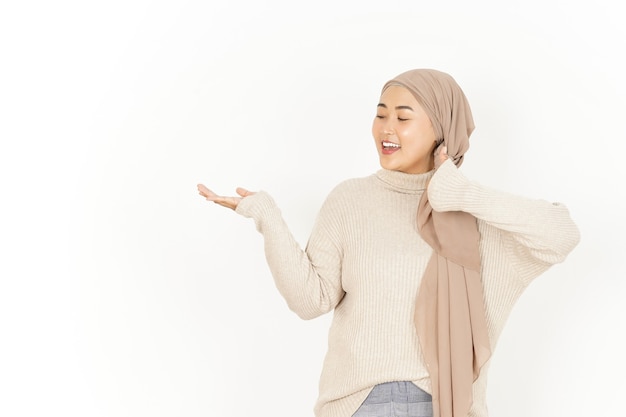 Apresentando o produto na palma da mão aberta de uma linda mulher asiática usando um hijab isolado no fundo branco