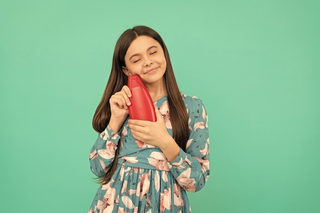 Apresentando produto cosmético para criança adolescente com gel de banho garota feliz segurando garrafa de xampu