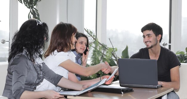 Apretón de manos de colegas sentados en el lugar de trabajo