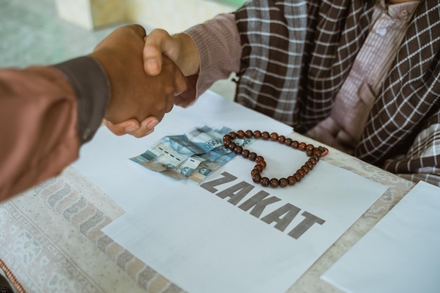 Apretón de manos con dinero como pago por la donación de zakat durante el ramadán