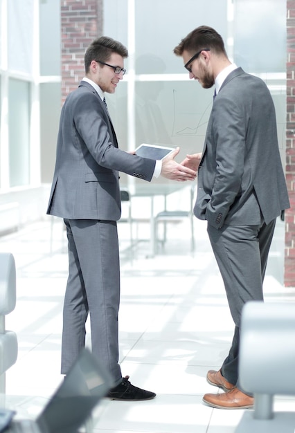 Apretón de manos de dos empleados de pie en el concepto de negocio de oficina