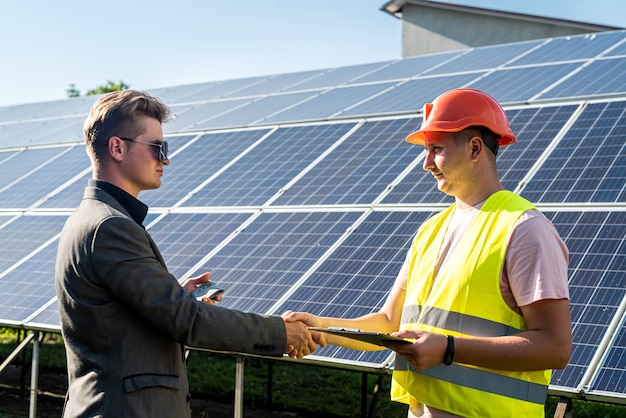 Apretón de manos de dos hombres después de la conclusión del acuerdo sobre el fondo de los paneles solares.