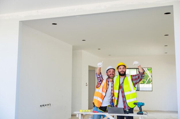 Apretón de manos Electricista e ingeniero de construcción equipo de hombre en uniforme de seguridad trabajando y planeando en el sitio de construcción