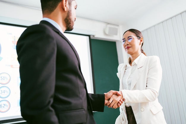 Apretón de manos de empresaria asiática con empresario el trabajo en equipo de fusiones y adquisiciones comerciales para una negociación exitosa Dos hombres de negocios se dan la mano con socios para celebrar acuerdos comerciales