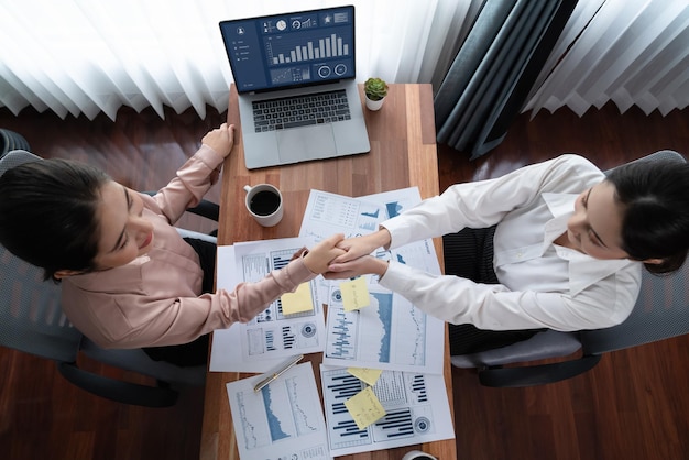 Foto apretón de manos de empresarias asiáticas de vista superior sobre escritorio entusiasta