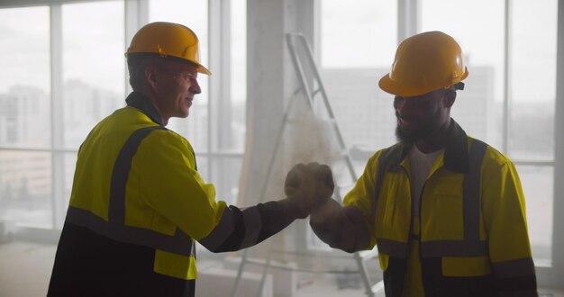 Apretón de manos de ingeniero y arquitecto multiétnico en el sitio de construcción