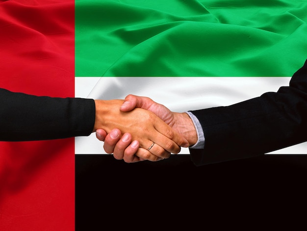 Apretón de manos de negocios en el fondo de la bandera de los Emiratos Árabes Unidos