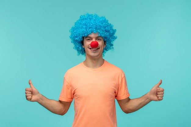 Aprilscherzkerl Clown glücklich zeigt sehr gutes Zeichen beide Hände blaue Haare aufgeregt lustige rote Nase