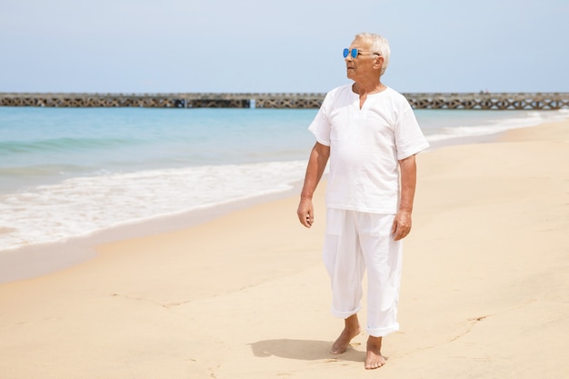 Aproveitando a aposentadoria. Homem feliz sênior caminhando na praia.