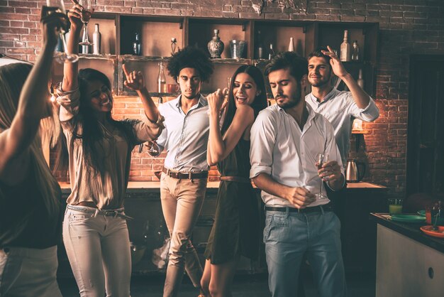 Aproveitando a melhor festa. jovens alegres dançando e bebendo enquanto aproveitam a festa em casa na cozinha