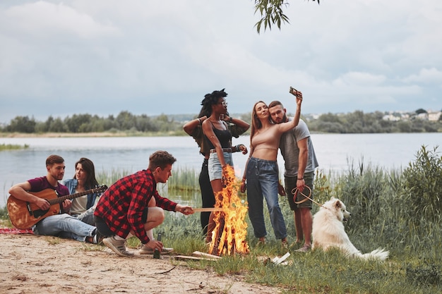 Aproveitando a natureza. Grupo de pessoas faz piquenique na praia. Os amigos se divertem no fim de semana.