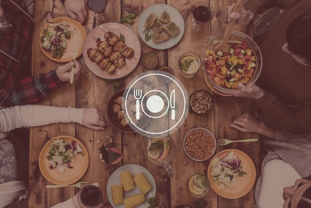 Aproveitando o jantar juntos. Vista superior de quatro pessoas jantando juntas enquanto estão sentadas à mesa de madeira rústica