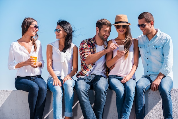 Aproveitando o tempo juntos. Grupo de jovens felizes, passando um tempo juntos sentados ao ar livre