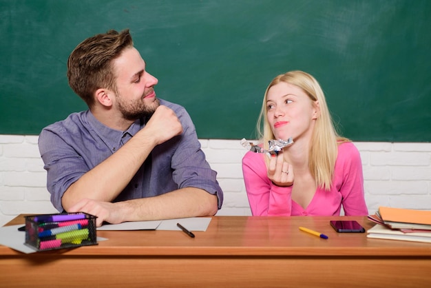 Aproveitando o tempo na faculdade garoto e garota sentam na sala de aula estudando na faculdade ou universidade amigos estudantes estudando universidade diversão na faculdade educação moderna se divertindo na faculdade alunos despreocupados