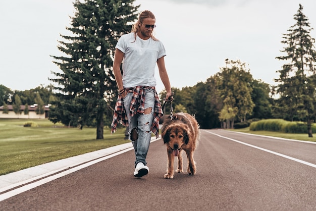 Foto aproveitando uma boa caminhada. comprimento total de um jovem bonito caminhando com seu cachorro enquanto passa o tempo ao ar livre