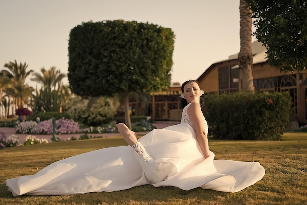 Aproveite seu dia Noiva vestido de casamento branco de luxo dia ensolarado fundo de natureza tropical Casamento trópico Mulher bonita feliz usar vestido incrível na cerimônia de casamento tropical Noiva exótica esticando o prado