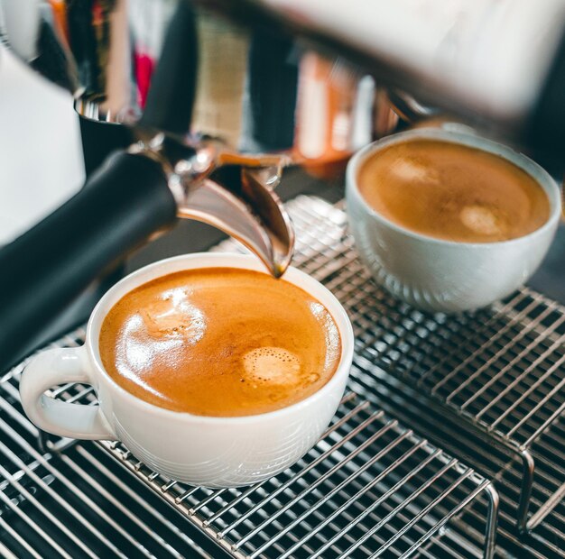 Aproximação da extração de café da máquina de café com um porta-filtro derramando café em uma xícara