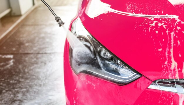 Aproximação da luz frontal de rosa brilhante lavada em autoatendimento, pulverização de água de alta pressão no vidro