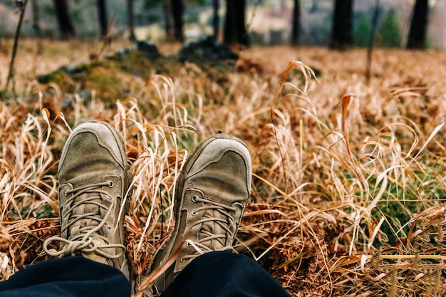 Foto aproximação das pernas de um alpinista em botas de caminhada pov vista de pernas fechadas no fundo do prado