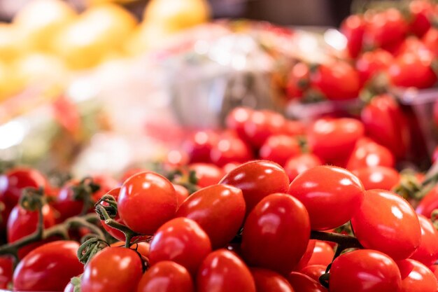 Aproximação de alguns tomates na banca do mercado juntamente com outros vegetais para uma dieta de baixa caloria ou para a dieta mediterrânica