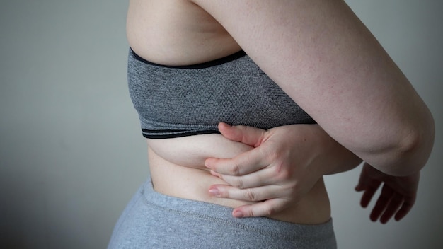 Aproximação de dobras de gordura na barriga grande de uma mulher com sobrepeso Conceito de dieta de obesidade feminina com sobrepeso e problemas de sobrepeso