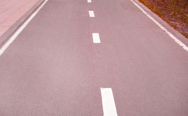 Aproximação de uma estrada de asfalto com uma linha de marcação intermitente Foco seletivo tingimento rosa