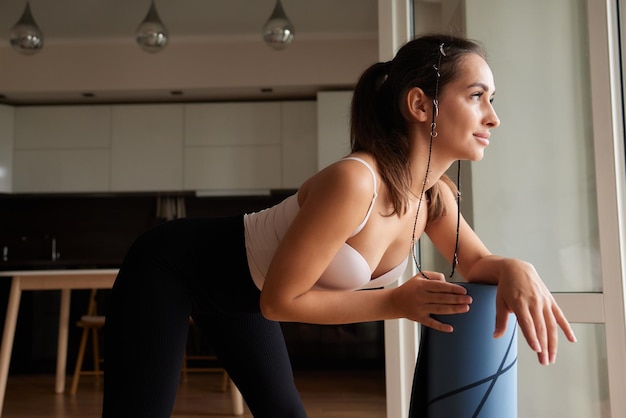 Aproximação de uma jovem atraente colocando um tapete azul de ioga ou fitness antes de se exercitar no estúdio Estilo de vida saudável