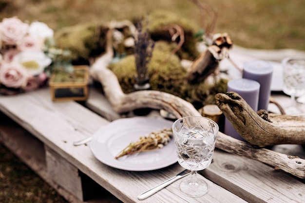 Aproximação de uma mesa de jantar de casamento, uma mesa feita de paletes de construção decorada com madeira flutuante e um