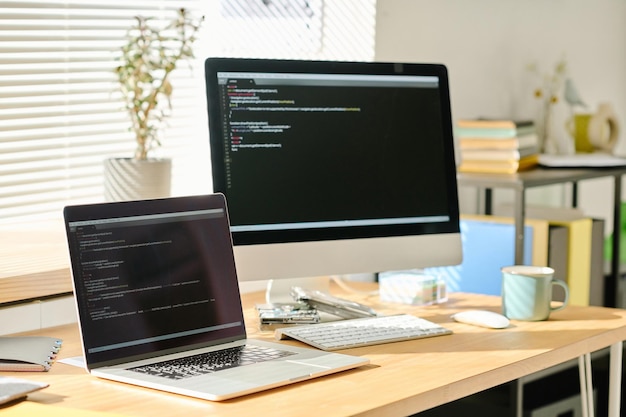 Aproximação do local de trabalho moderno com computadores com códigos na tela do escritório