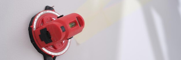 Foto aproximação do nível de laser de construção vermelho fixado no dispositivo de medição profissional de parede branca para