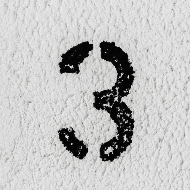 Foto aproximação do número 3 pintado de preto na parede texturizada cinza