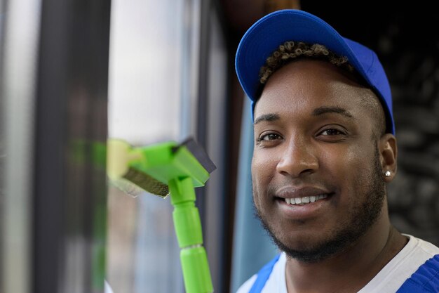 Foto aproximação do rosto feliz de um trabalhador preto uniformizado azul limpando as instalações