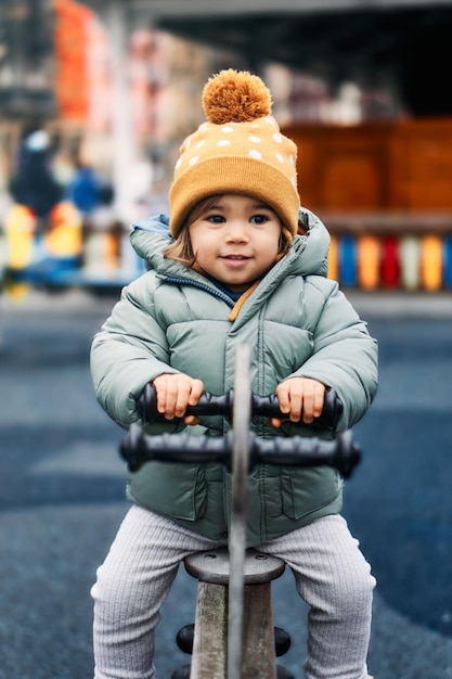 Aproximação vertical de uma criança feminina vestindo roupas de inverno enquanto brincava no parquinho